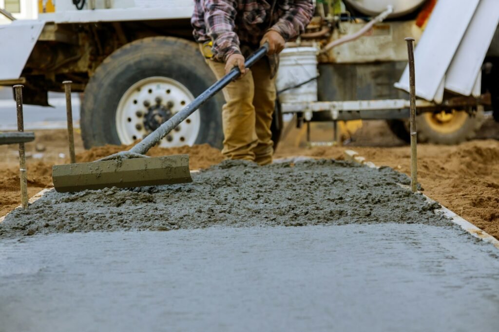 Construction worker pour cement for sidewalk in concrete works with mixer truck with wheelbarrow at